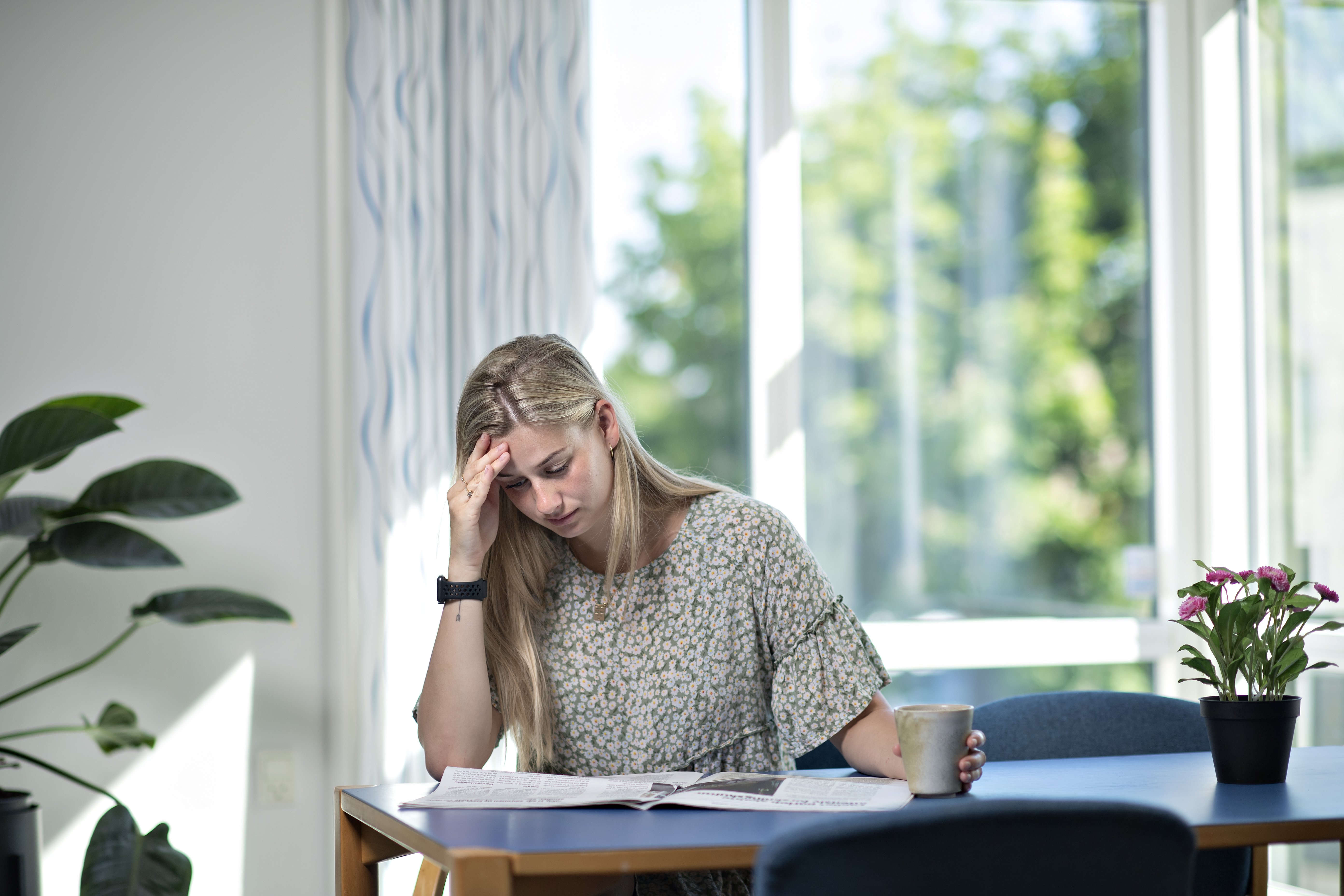En kvinde sidder ved et bord og laeser en avis