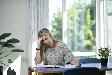 En kvinde sidder ved et bord og laeser en avis